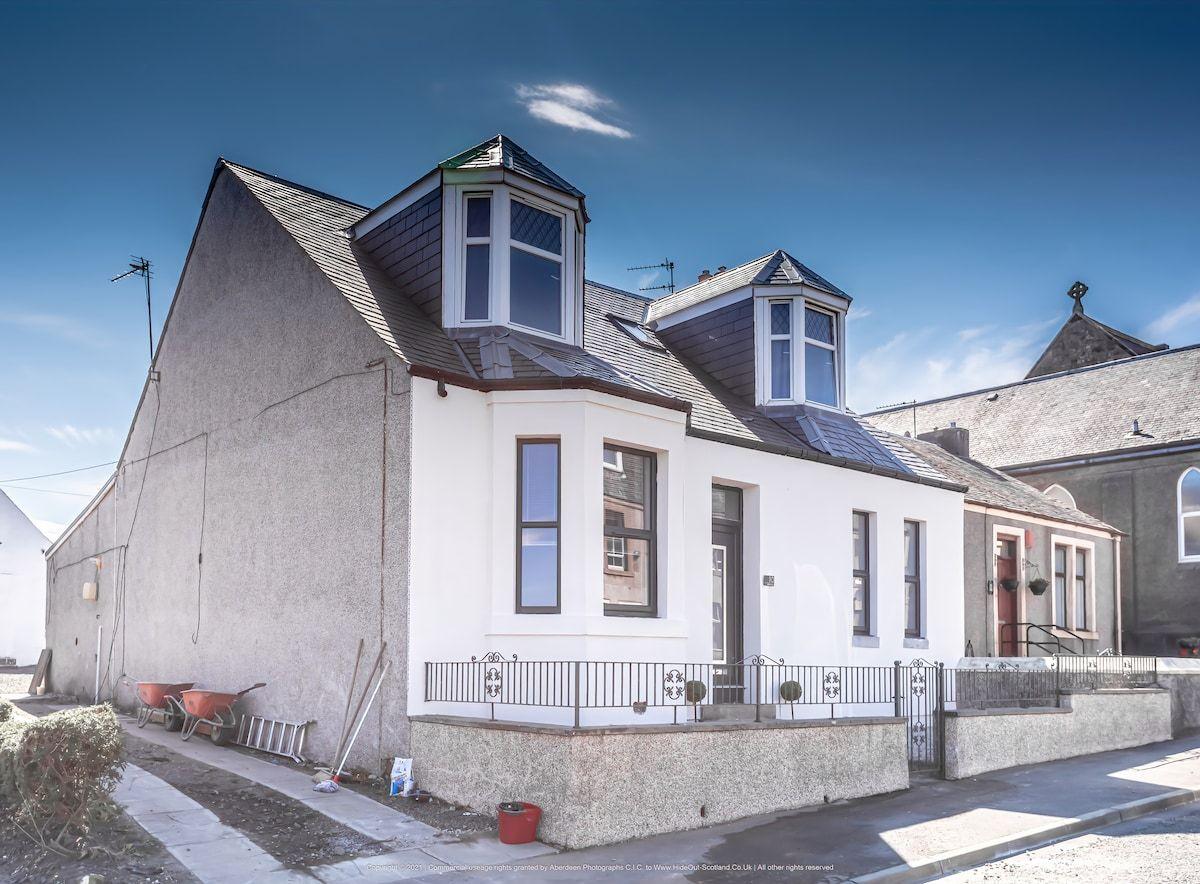 No.10 Station Road, a white house with two bay dormers, under a blue sky